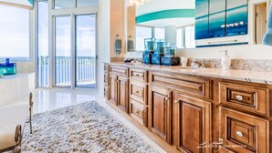 A spacious kitchen with wooden cabinets, a marble countertop, and a large window overlooking a balcony.