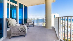 A balcony with wicker furniture, a view of the ocean, and a clear sky.