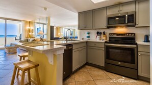 A modern kitchen with a large island, stainless steel appliances, and a view of the ocean. - Perdido Sun 816 (Pensacola)