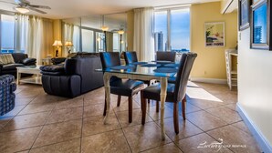 A spacious living room with a glass-top dining table, leather sofas, and a ceiling fan. - Perdido Sun 816 (Pensacola)