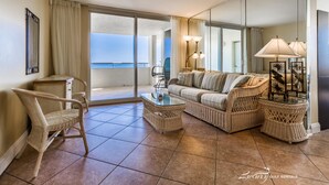 A spacious living area with a large window, wicker furniture, and a glass coffee table. - Perdido Sun 816 (Pensacola)