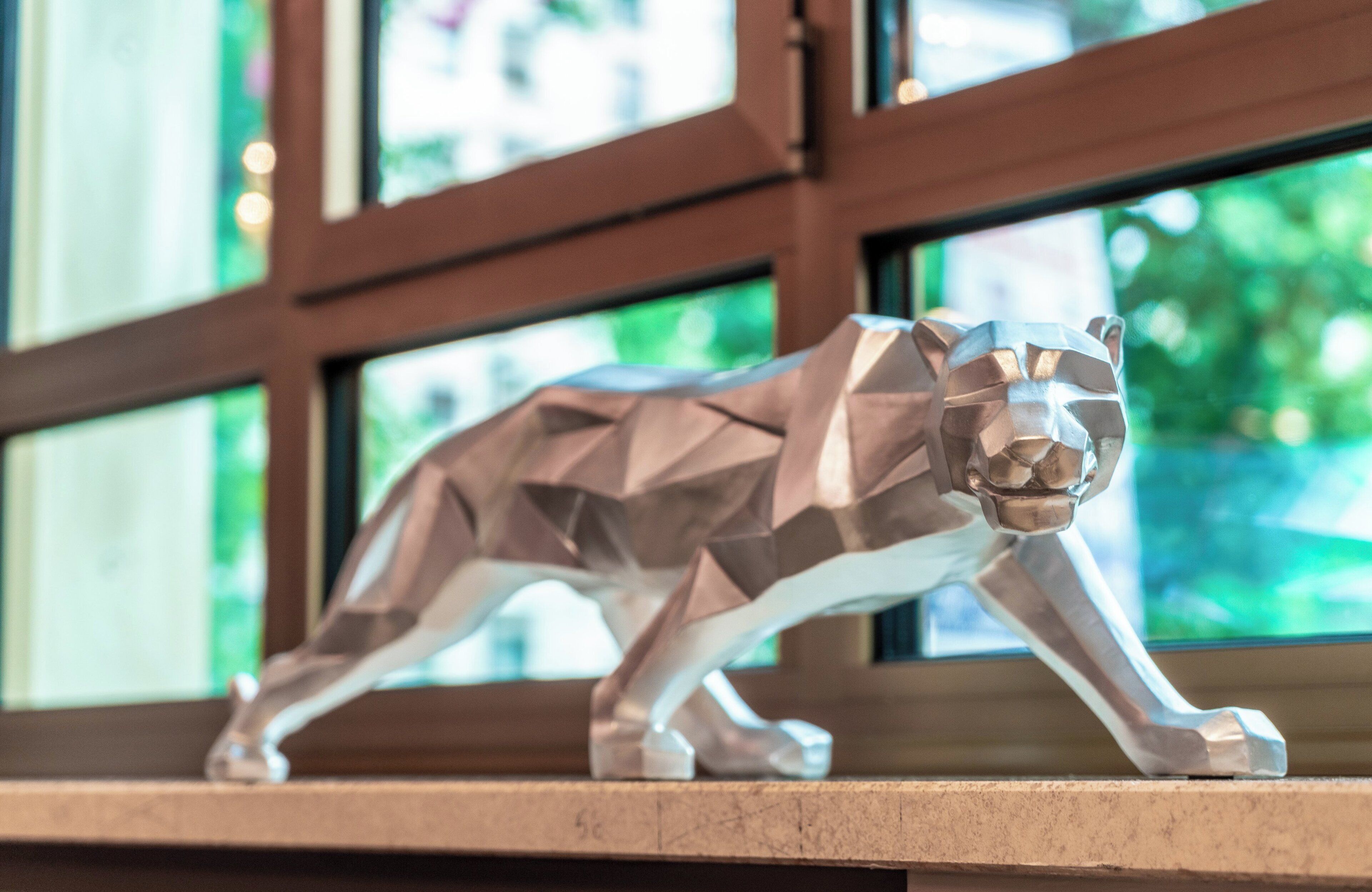 A geometric sculpture of a lion on a ledge.