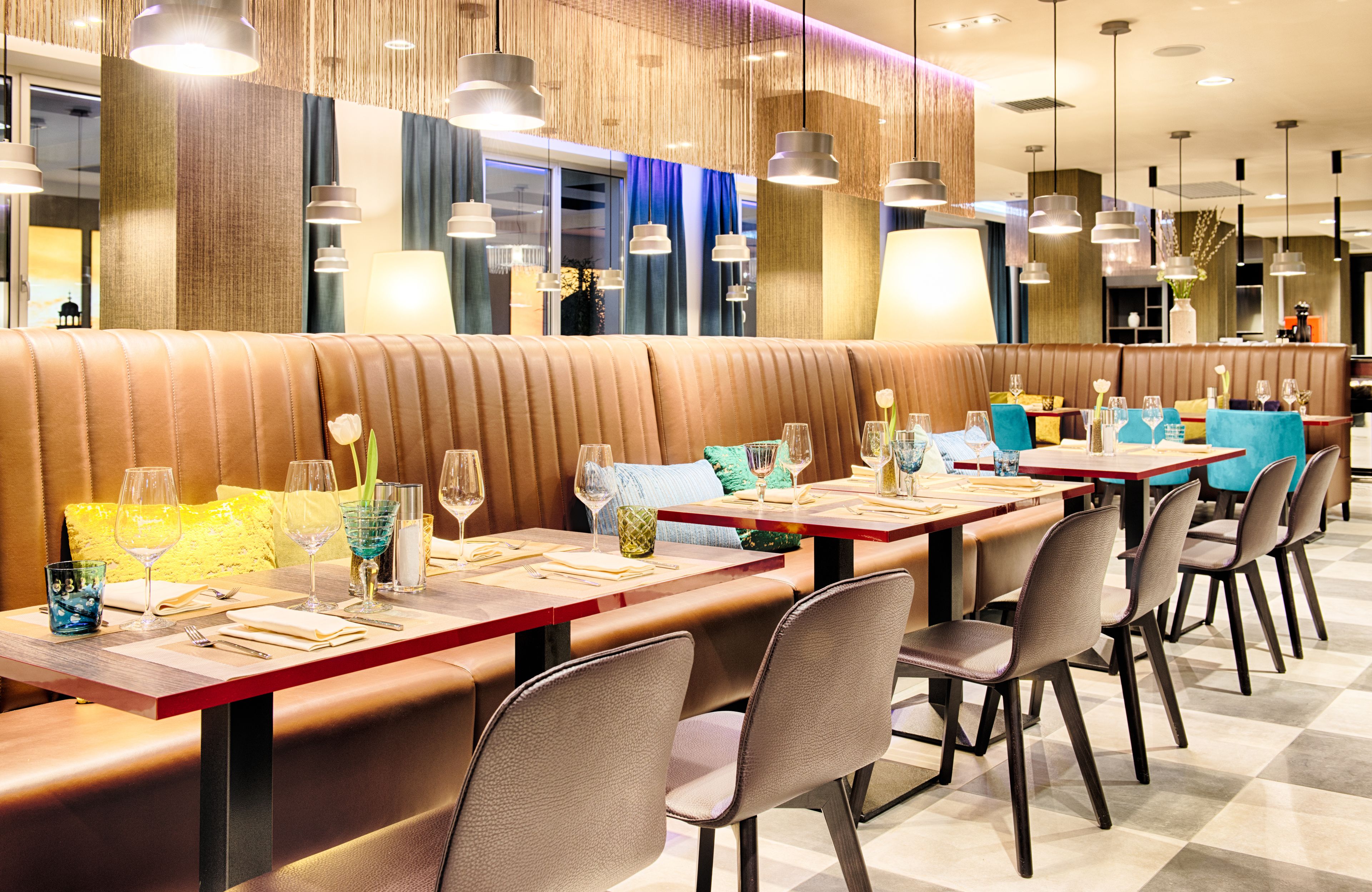Un restaurant avec des banquettes et des tables, chacune étant équipée de couverts, de verres et de serviettes.