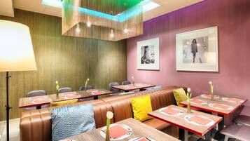 A restaurant with booths and tables, each with red placemats and white plates.