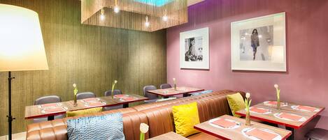 Un restaurante con cabinas y mesas, cada una con manteles individuales rojos y platos blancos.