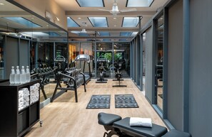 Un gimnasio moderno con equipamiento de ejercicio, una banca y una estación de agua.