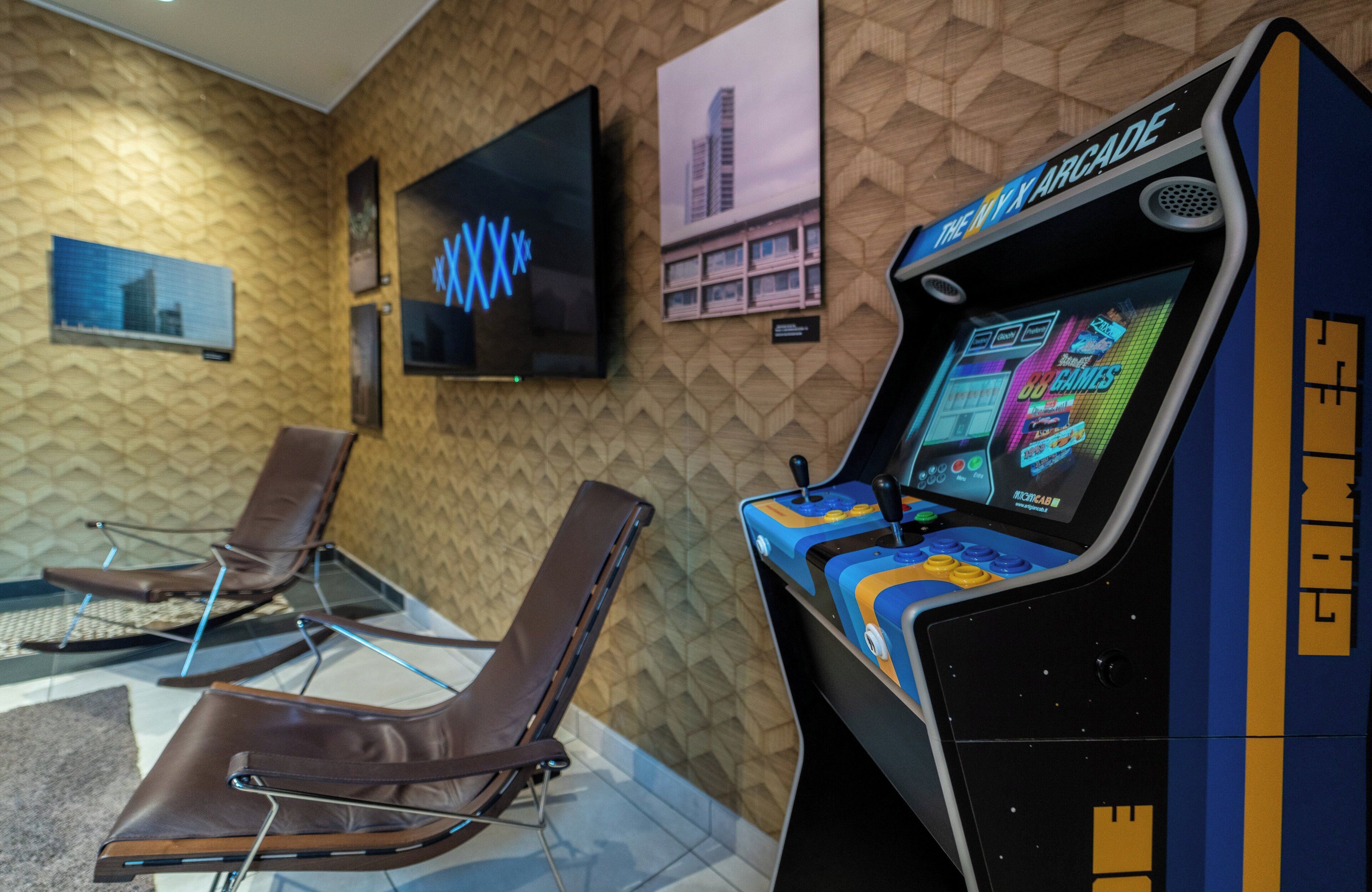 A gaming arcade with a neon sign, a television, and two reclining chairs.