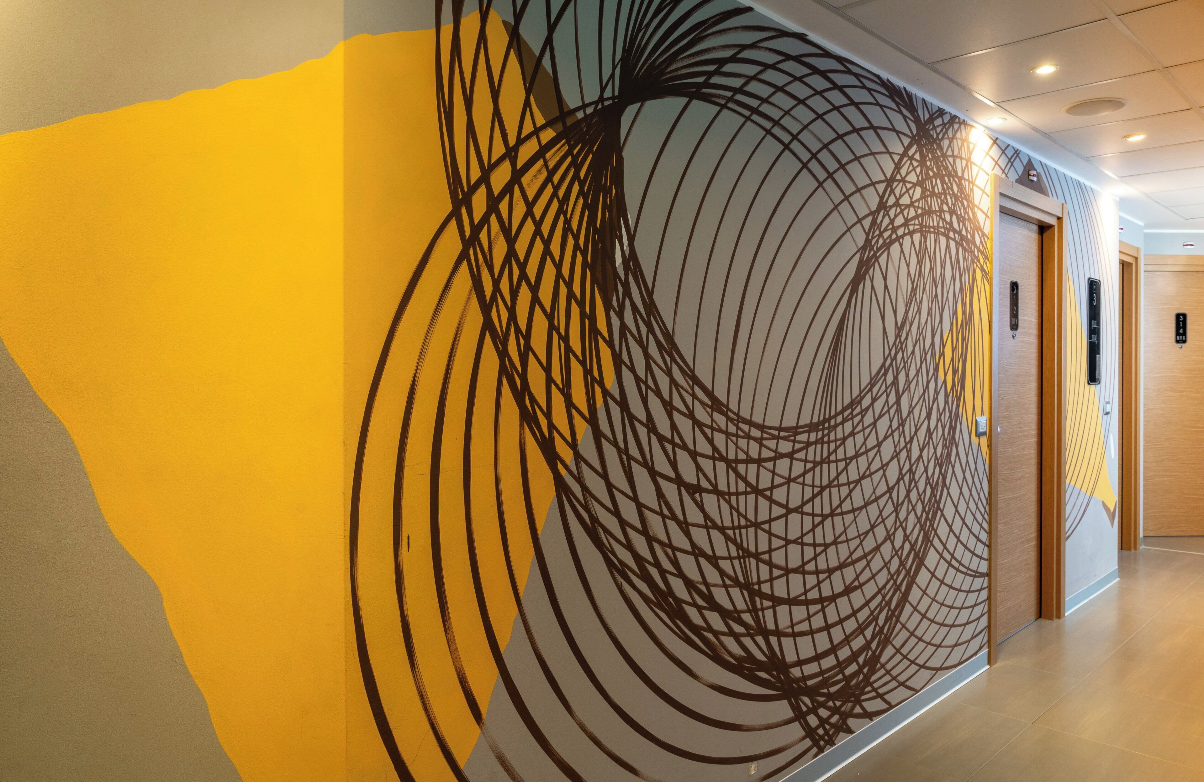 A hallway with a modern wall design featuring concentric circles and a wooden door.
