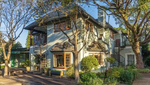 A two-story house with a wooden deck, a small pool, and a garden with various plants. - Hedge House (Cape Town)