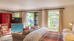 A bedroom with a large bed, a television, a red wardrobe, and a blue cabinet. - Hedge House (Cape Town)