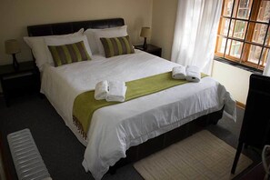 A neatly made bed with white linens, two pillows, and two folded towels. - Ebony and Ivory (Bloemfontein)