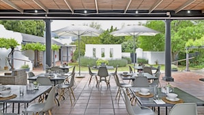 An outdoor patio with tables and chairs, umbrellas, and a garden view. - Mont d'Or Franschhoek (Franschhoek)