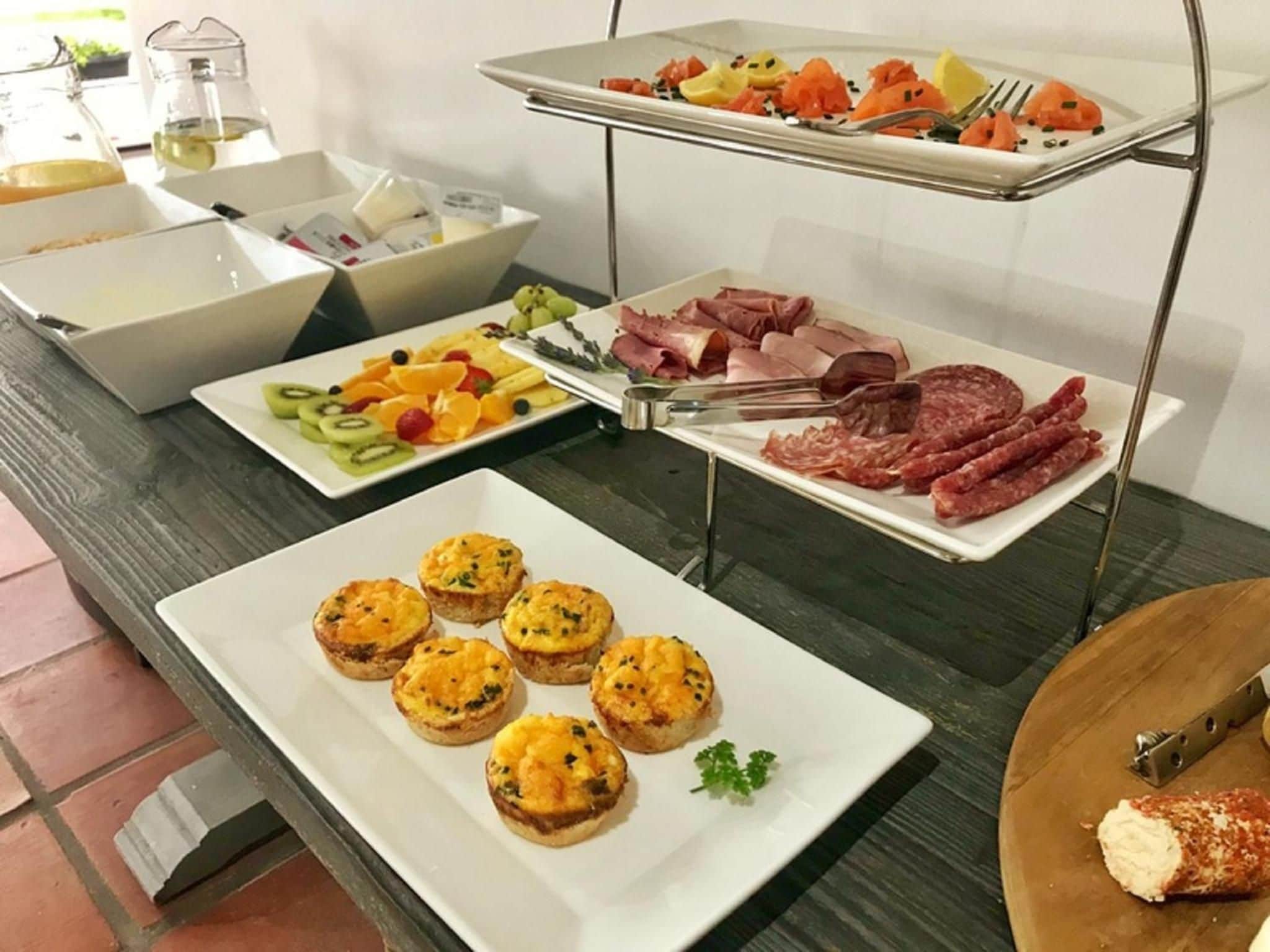 A buffet table with various food items including fruits, meats, and pastries.