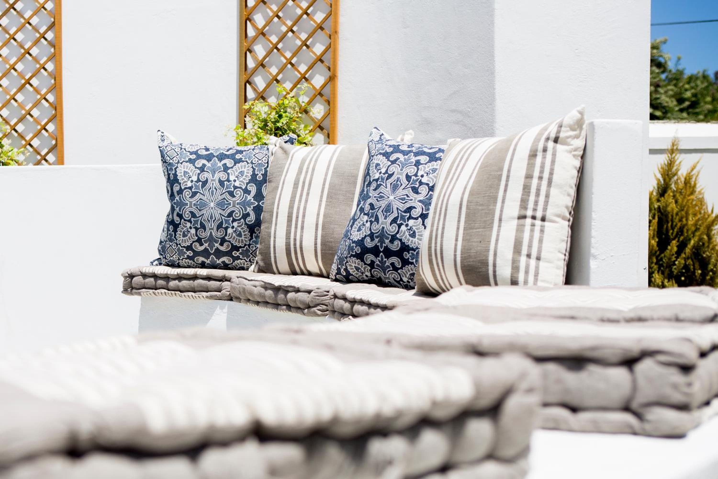 A white outdoor seating area with a patterned cushion and a striped cushion.