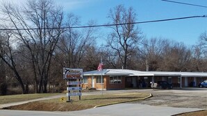A motel with a signboard, an American flag, and a parking lot.