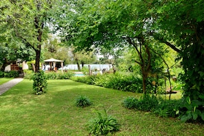 Ein Garten mit einem Pavillon, einem Pool und einem Weg.