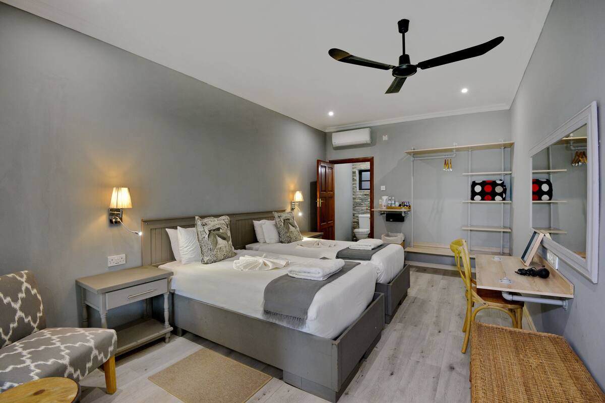 A modern hotel room with a large bed, bedside tables, a desk, and a chair.