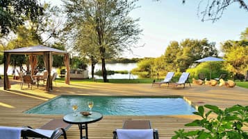 Una piscina al aire libre, sombrillas, sillones reclinables de piscina