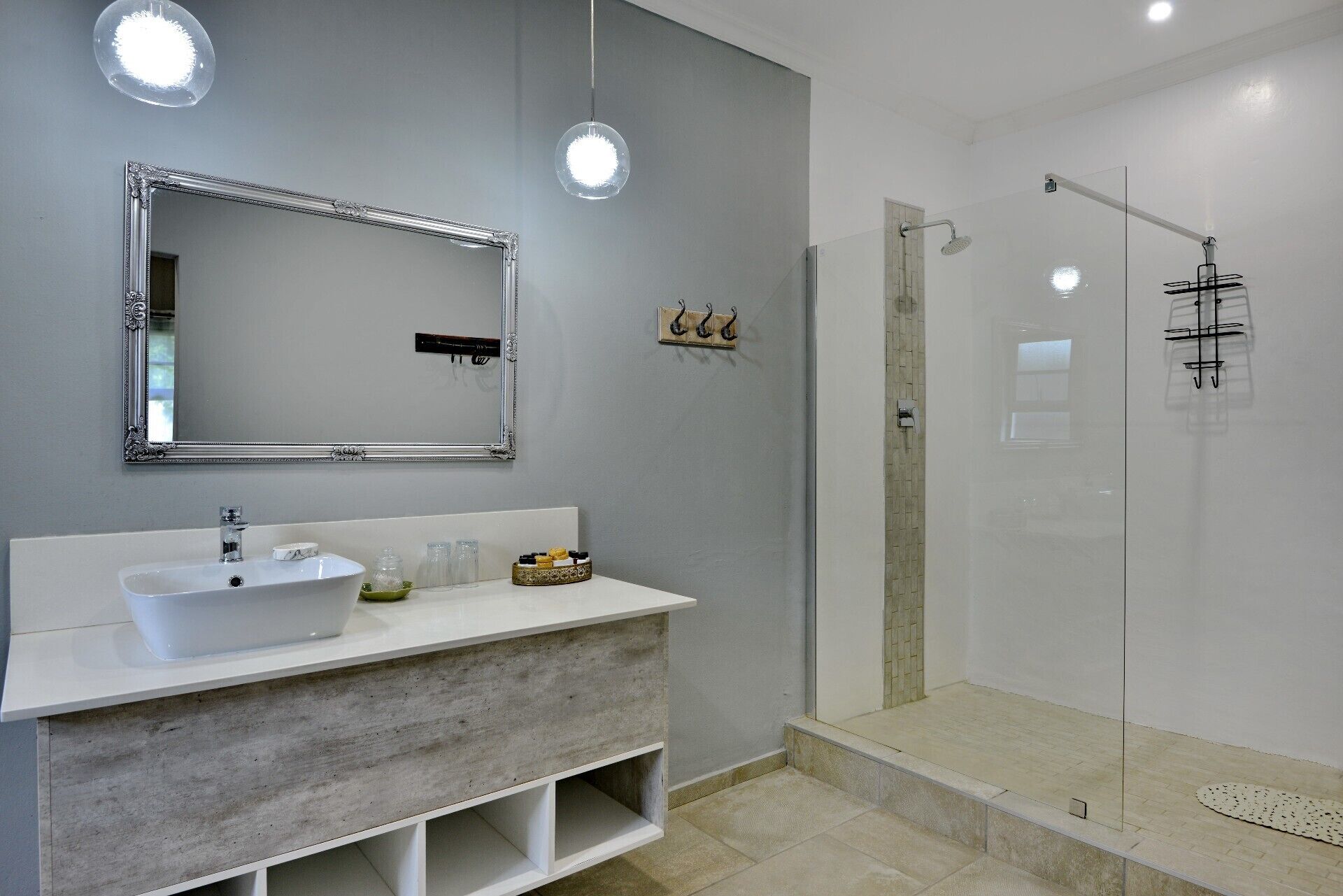 A modern bathroom with a large mirror, a white sink, and a glass-enclosed shower.