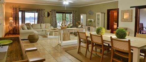 Amplia sala de estar con sofá, mesa de comedor y sillas. Hay una cocina con pileta y ventana con vistas panorámicas.