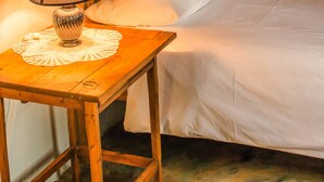 A neatly made bed with white linens, a wooden headboard, and a bedside table with a lamp.