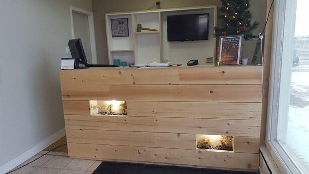 A reception desk with a flat-screen TV above it, a signboard, and a small Christmas tree. - Safari Inn Motel (Swift Current)