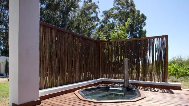 A wooden deck with a hot tub and a bamboo fence. - Rest Chabivin Self Catering (Stellenbosch)