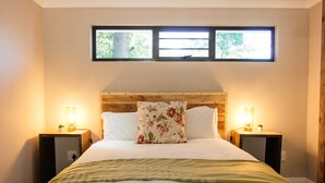 A neatly made bed with a floral pillow, two bedside lamps, and a window above. - Rest Chabivin Self Catering (Stellenbosch)