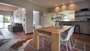 Un soggiorno moderno con zona pranzo, cucina e angolo salotto con divano e poltrone.