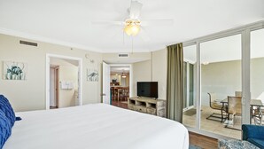 A hotel room with a large bed, a television, a balcony with a table and chairs, and a dining area in the background. - Destin West Resort by Panhandle Getaways (Fort Walton Beach)
