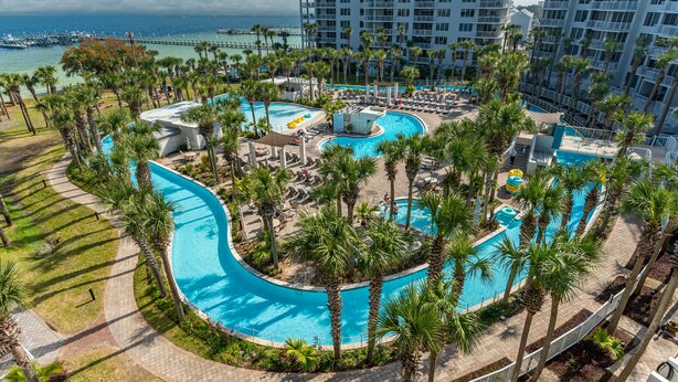 A resort with a large central pool, palm trees, and a marina in the background. - Destin West Resort by Panhandle Getaways (Fort Walton Beach)