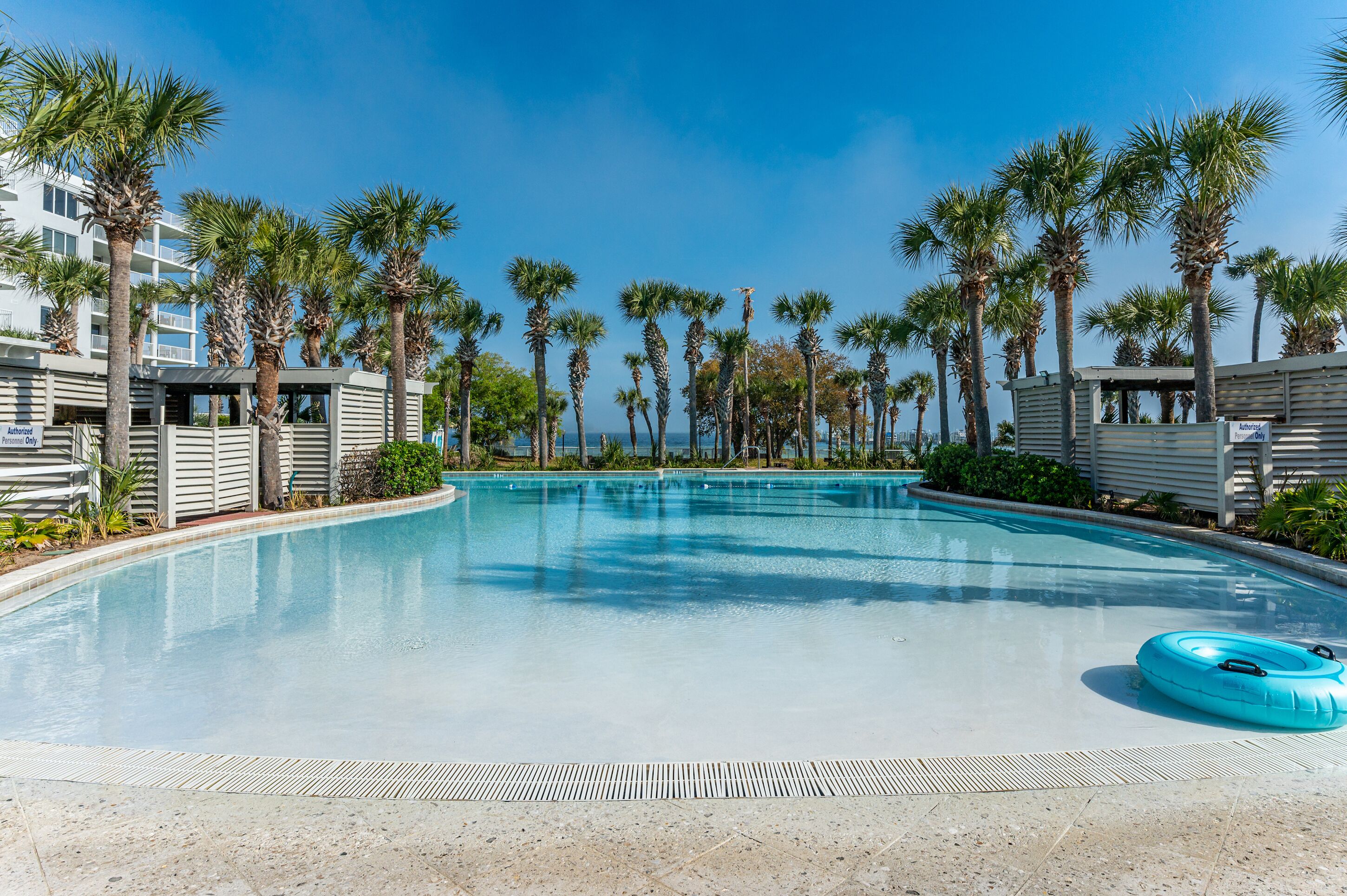 A swimming pool surrounded by palm trees and a building with a modern design.