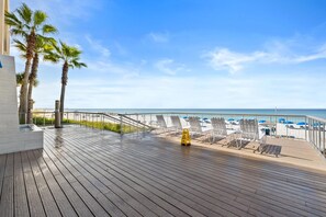 A wooden deck with lounge chairs and a caution sign, overlooking a beach with umbrellas. - Palazzo Beach Resort by Panhandle Getaways (Panama City Beach)