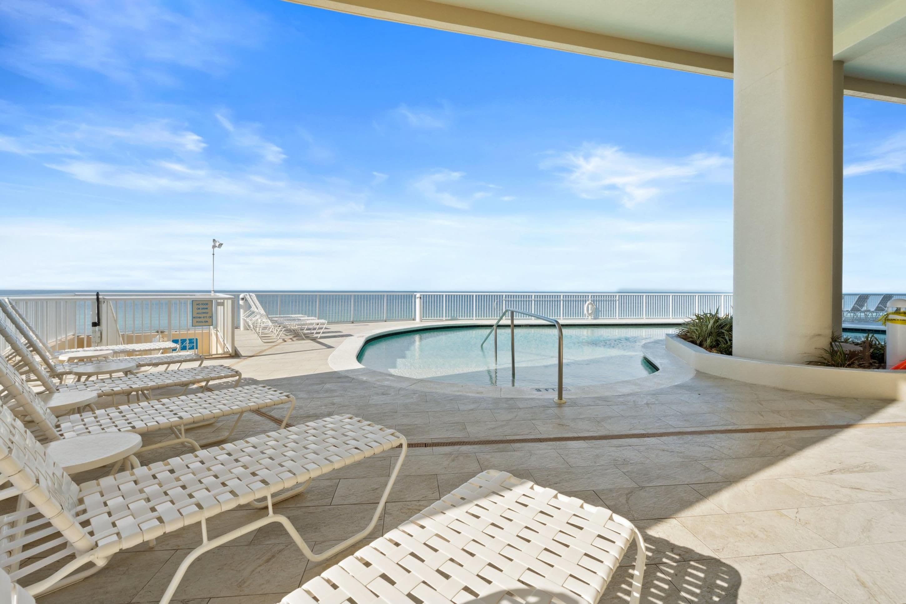 Zona de piscina con sillones de descanso y vista al océano.