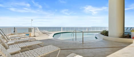 Zona de piscina con sillones de descanso y vista al océano.