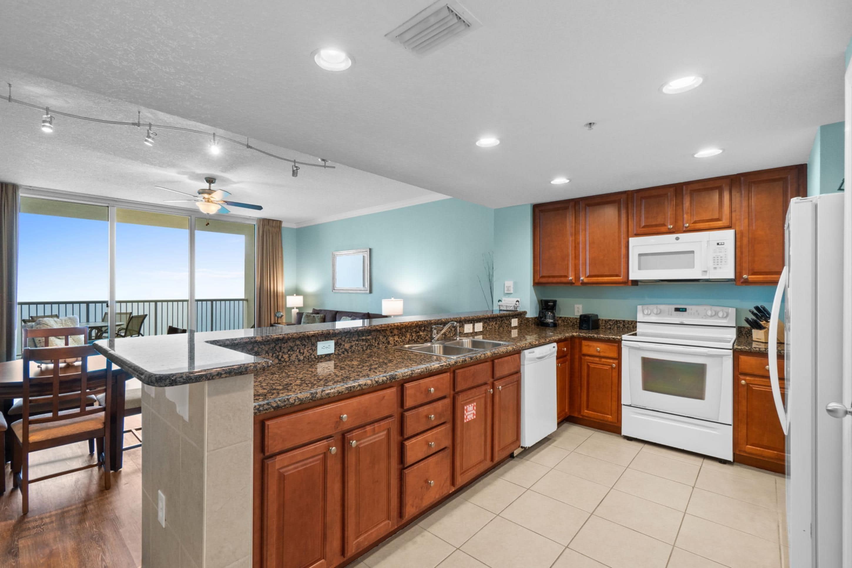 A modern kitchen with granite countertops, wooden cabinets, and stainless steel appliances.