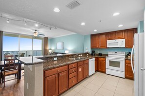 A modern kitchen with granite countertops, wooden cabinets, and stainless steel appliances. - Palazzo Beach Resort by Panhandle Getaways (Panama City Beach)