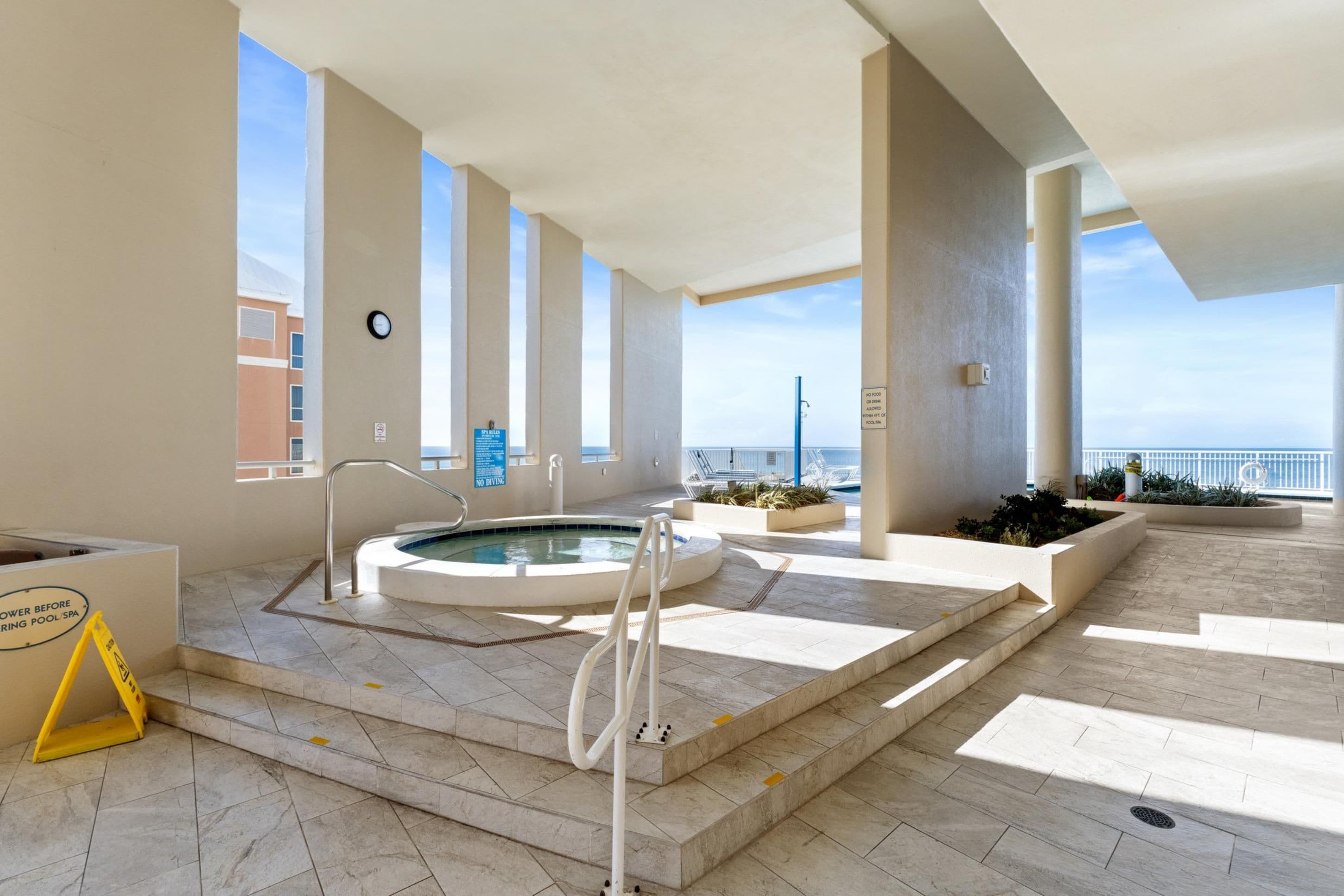 A modern indoor pool area with a hot tub, clear views of the sea, and a no diving sign.