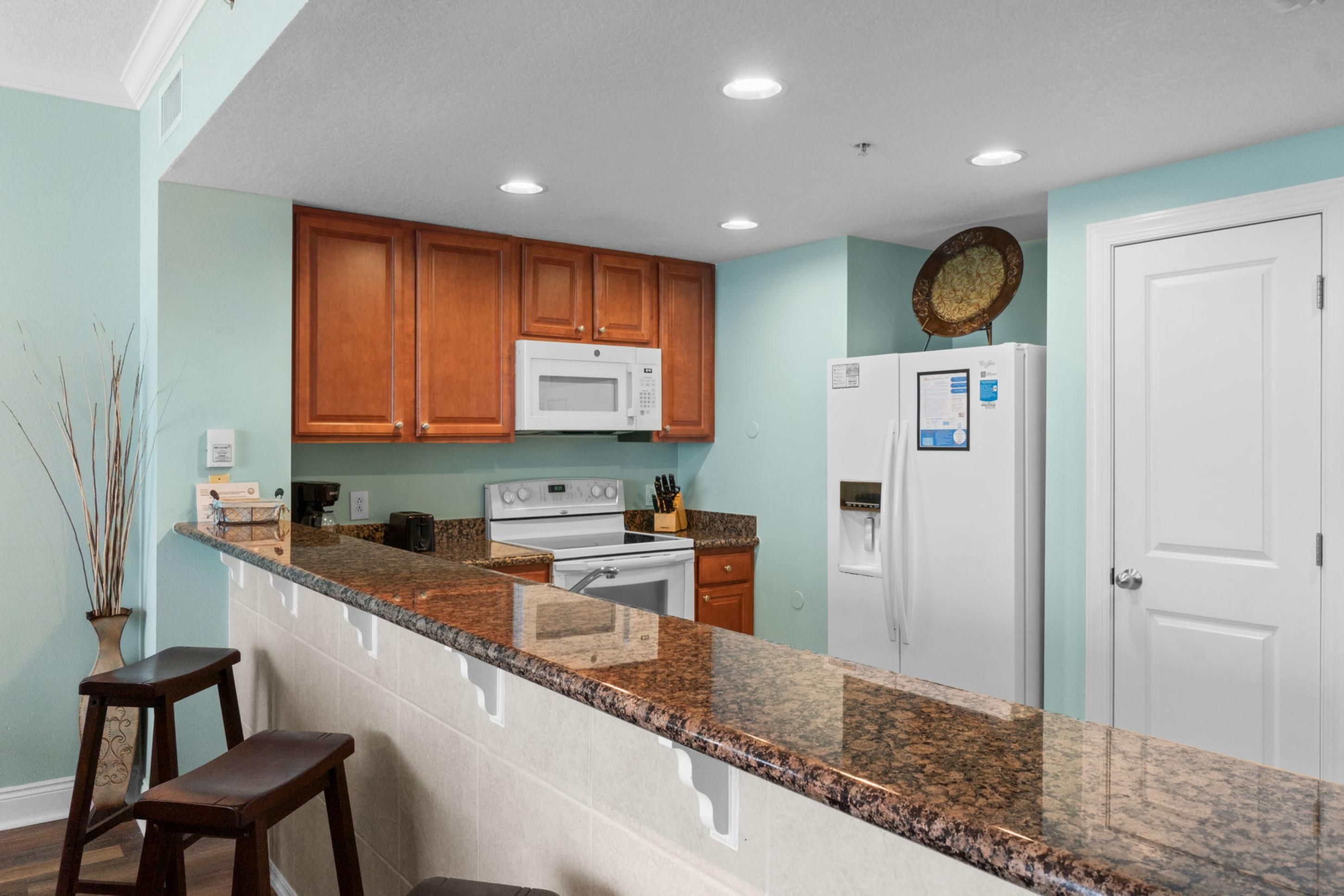 A kitchen with wooden cabinets, a white microwave, a stove, and a refrigerator.