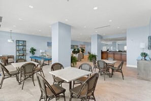 A spacious dining area with high ceilings, modern furniture, and a view of the kitchen in the background. - Palazzo Beach Resort by Panhandle Getaways (Panama City Beach)