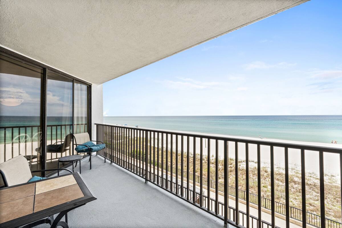 A balcony with a view of the beach and ocean.