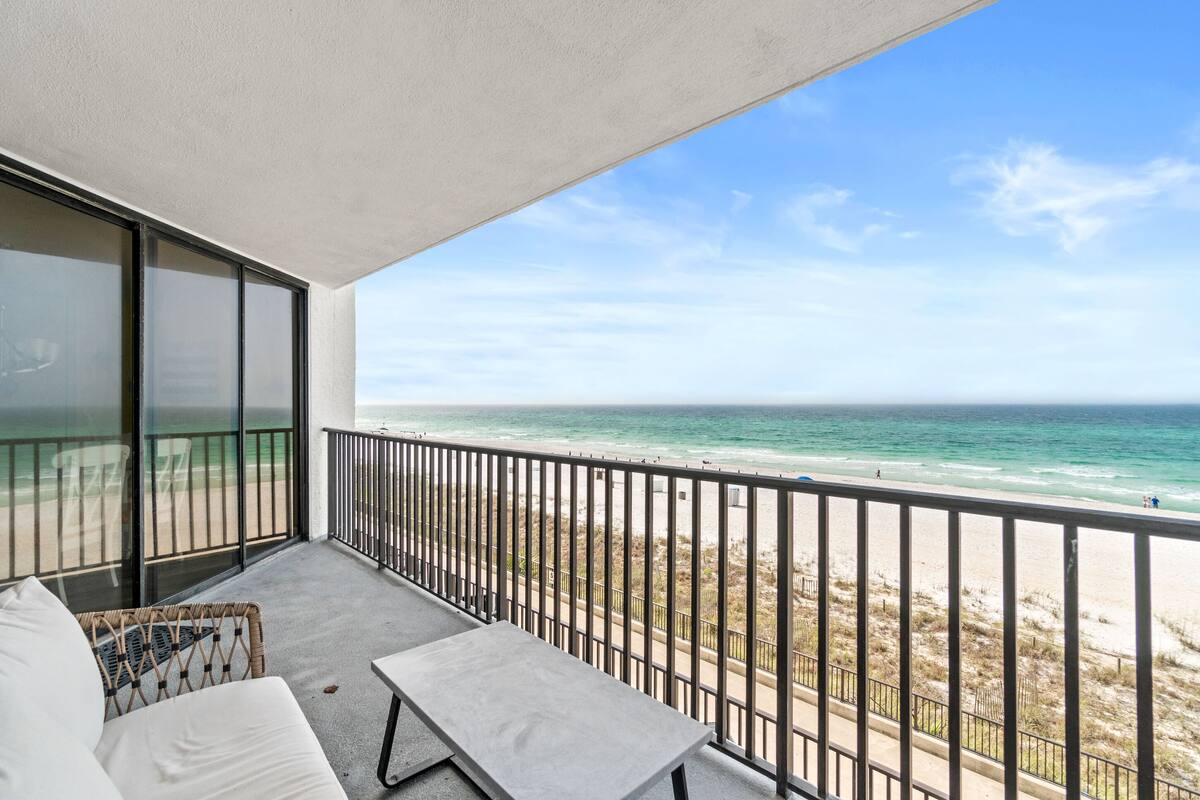 A balcony with a view of the beach and ocean.