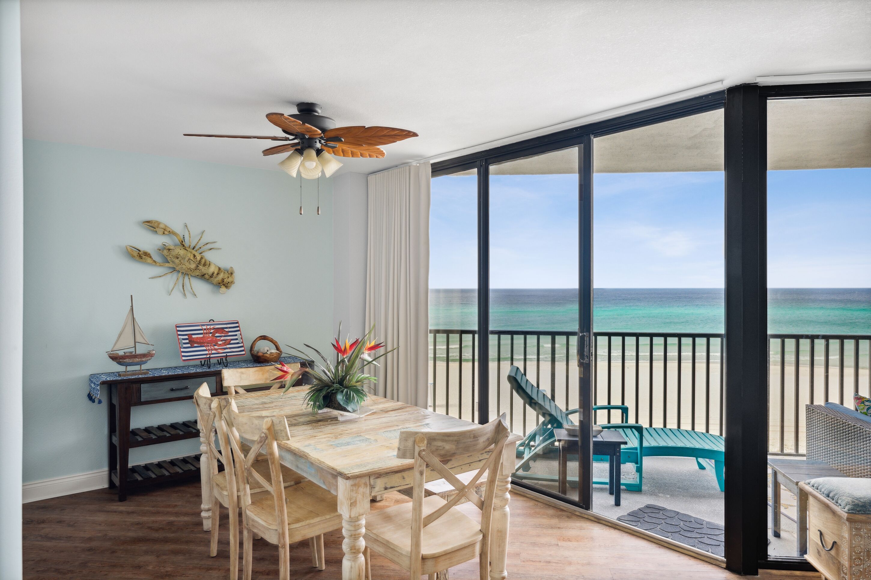 A dining area with a view of the ocean, a ceiling fan, and a table with chairs.