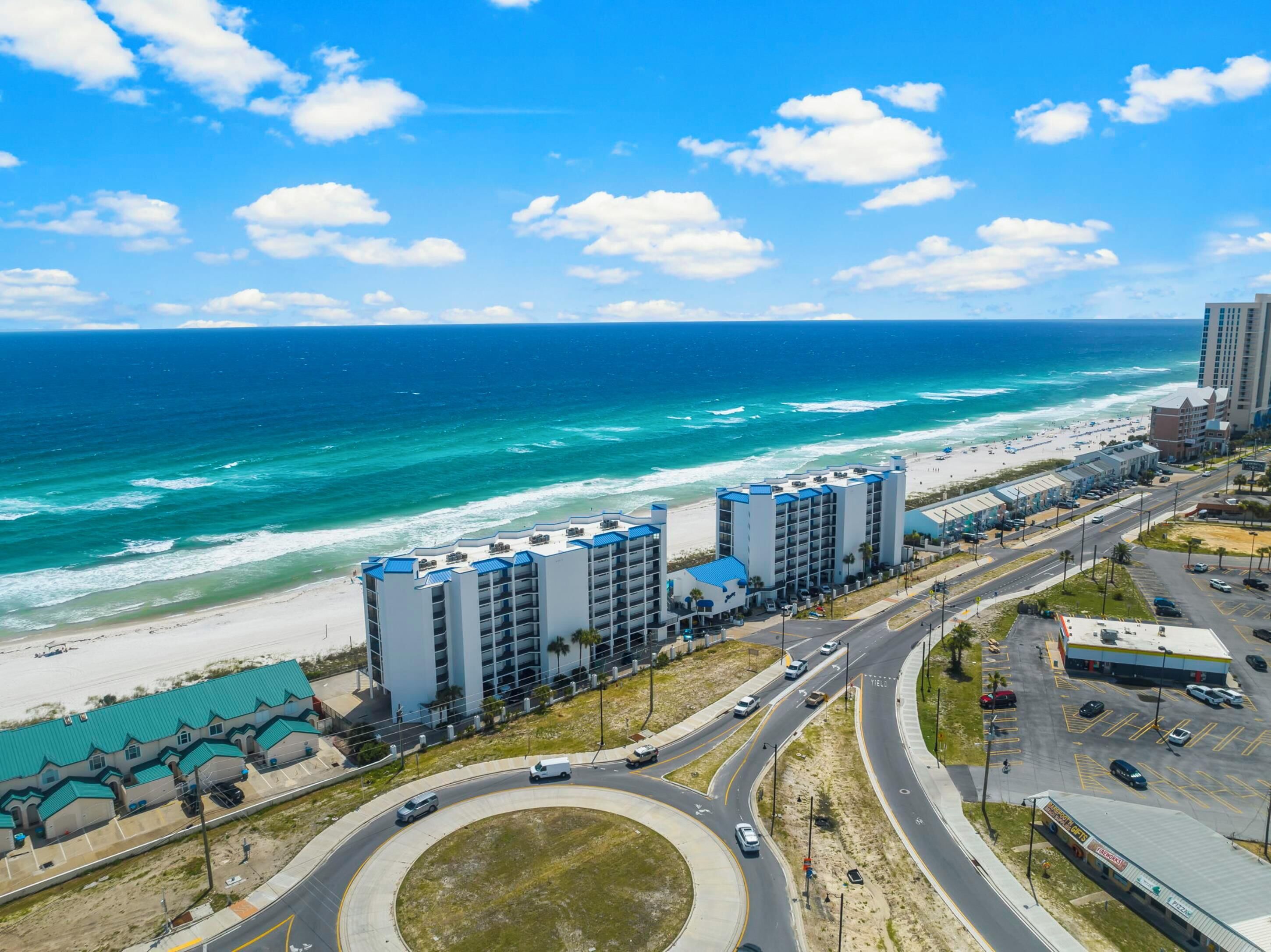 Ein Hotel an der Küste mit mehreren Etagen, Blick auf den Strand und einem Parkplatz.