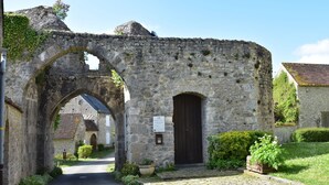 Un vieux bâtiment en pierre, avec une porte en bois sombre, une arche et une enseigne.