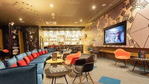 Un espace détente avec un canapé, des fauteuils, un téléviseur et un bar.