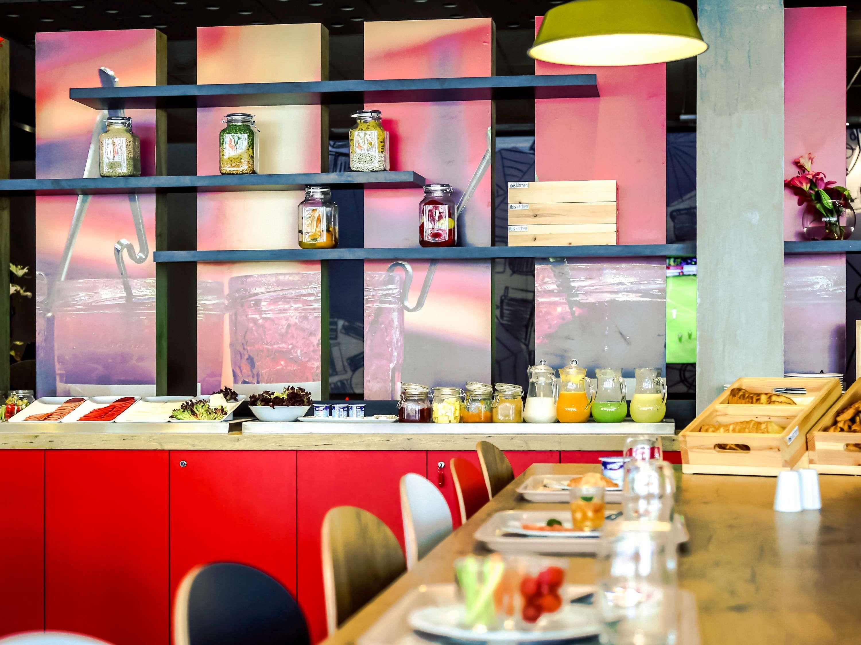 A restaurant interior with a long counter, shelves with jars, and a red wall.
