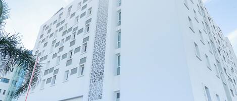 A modern hotel with a white facade, a red entrance, and a visible IDIS sign.