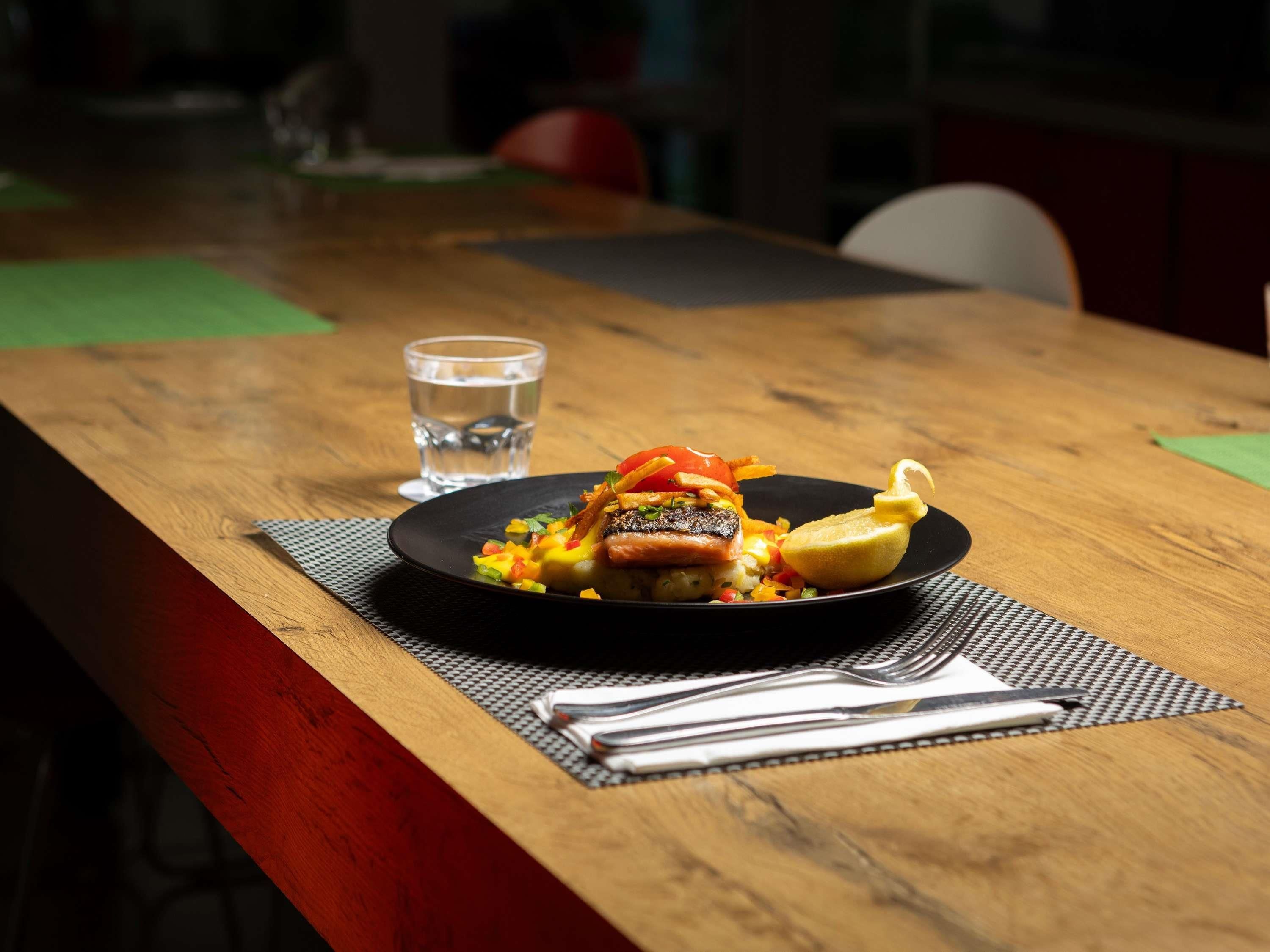 Une table en bois avec une assiette de nourriture, un verre d’eau et une serviette.
