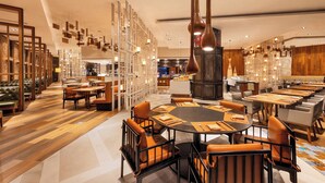 Un restaurant moderne avec des tables rondes, des fauteuils en cuir et un espace de restauration central.